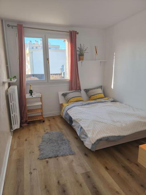 une chambre avec un lit et une grande fenêtre dans l'établissement Charmant appartement cosy, à Bondy