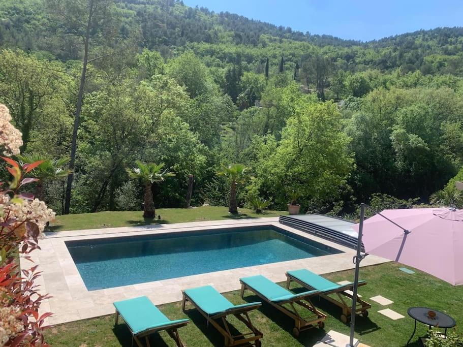 a swimming pool with two chairs and a umbrella at Agréable Studio entre mer & montagne piscine privé in Le Bar-sur-Loup