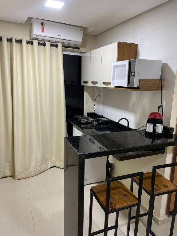 a kitchen with a counter with two chairs and a microwave at Studio Pé na Areia 2 in Ilhéus