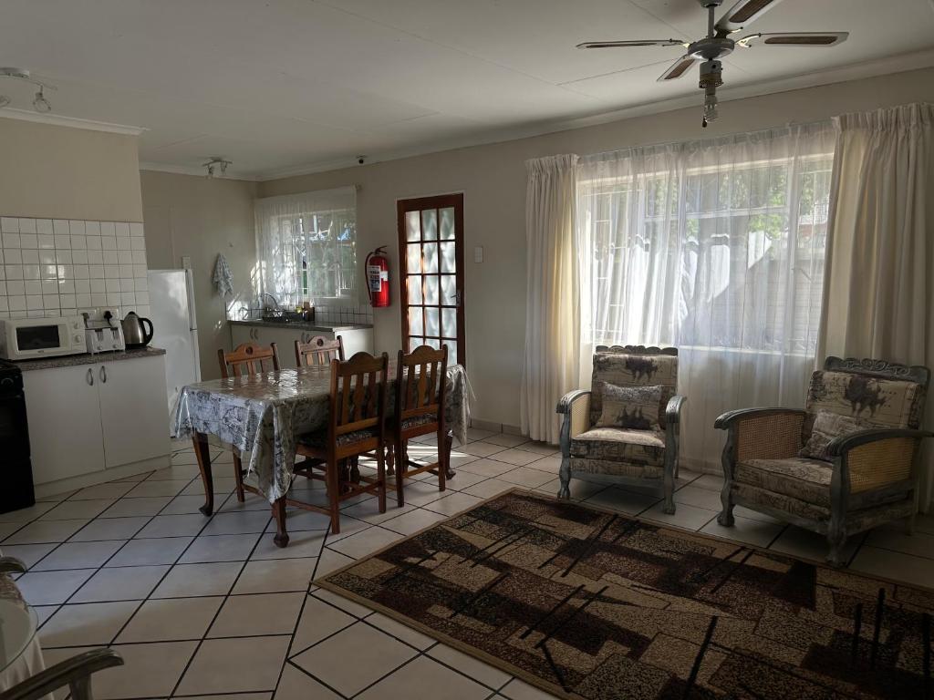 a living room with a table and chairs and a kitchen at Guesthouse 52 in Groblersdal