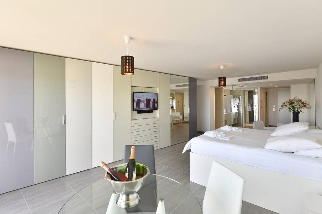 une chambre blanche avec un lit et une table en verre dans l'établissement NAUTILIA 106 - Supérieure Luxe avec Jacuzzi 2 personnes, au Cap d'Agde