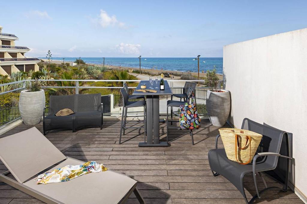 un patio avec une table et des chaises et l'océan dans l'établissement NAUTILIA 204 - Supérieure Luxe - 2 personnes, au Cap d'Agde