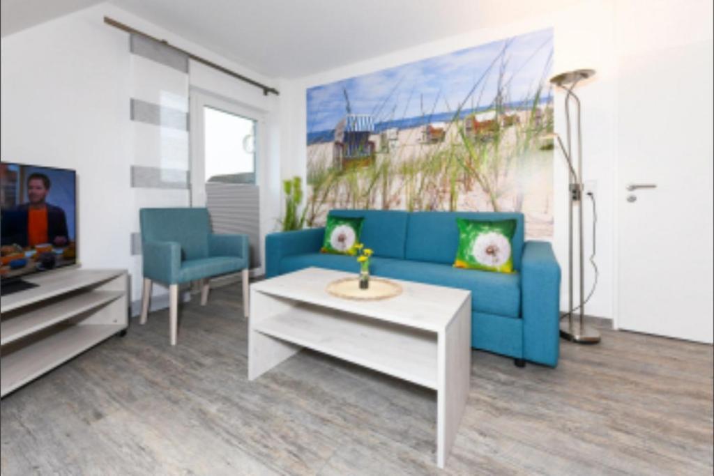 a living room with a blue couch and a table at Haus Strandkorb FeWo Strandkob 8 in Bensersiel