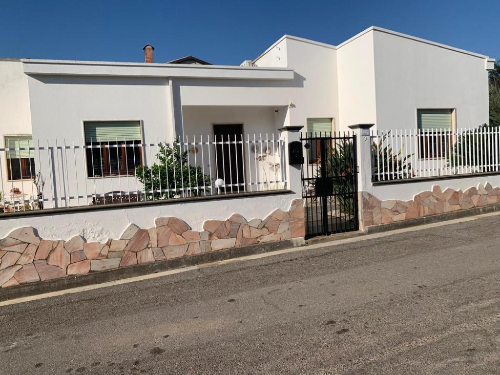 a white house with a fence on a street at Casa Ohana in Serramanna