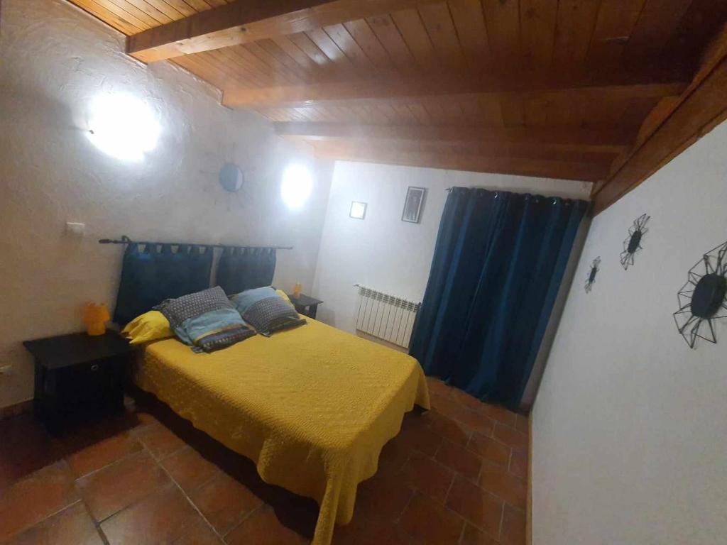 - une chambre avec un lit jaune et des rideaux bleus dans l'établissement maison de village, à Vendres
