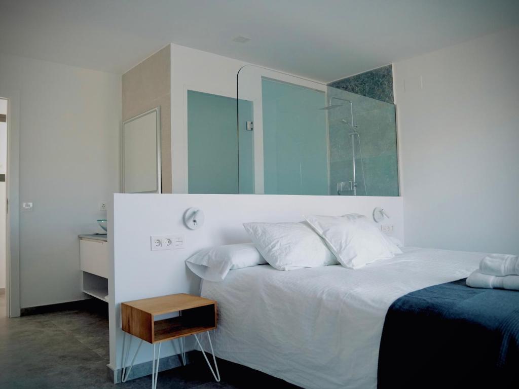 Un dormitorio con una gran cama blanca y una mesita de noche. en Casa rural Atalanta de la Vera, en Jaraíz de la Vera