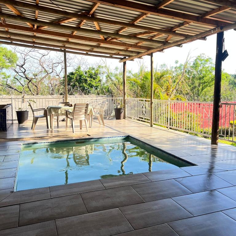 a patio with a table and chairs and a swimming pool at Sable Holiday Home in Hazyview