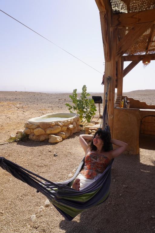 una donna sdraiata su un'amaca con un bambino di Desert Days mud cabin's Resort a Zuqim