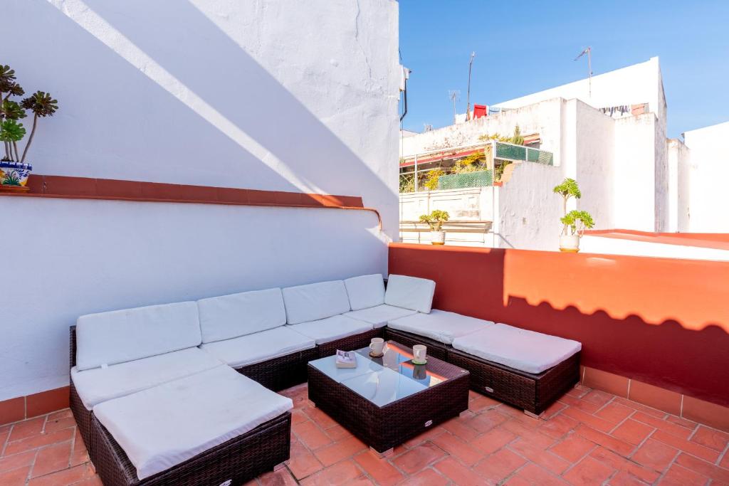 a patio with a couch and a table on a balcony at Holi-Rent Penthouse Peñuelas in Seville