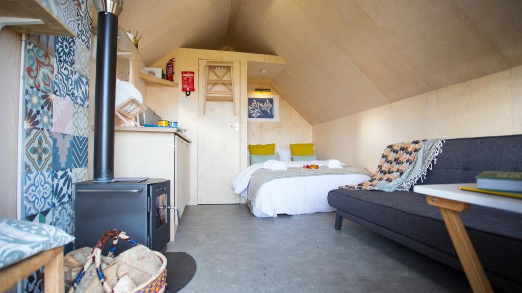 アルンマスにあるSt Hilda Beach Hut Alnmouthのベッドとソファ付きの小さな屋根裏部屋です。