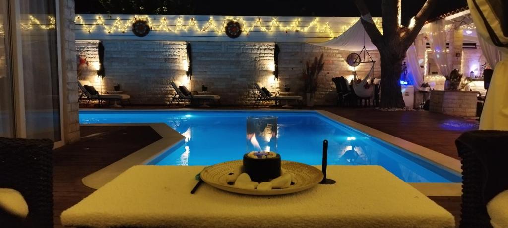 a candle on a table next to a swimming pool at Villa Maria Lagonissi - Private first floor Villa in Kalívia Thorikoú