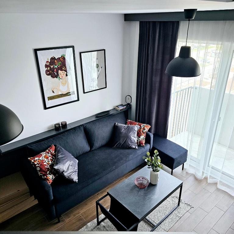 a living room with a black couch and a table at Apartament Wrocław Promenady in Wrocław