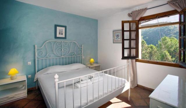 ein blaues Schlafzimmer mit einem Bett und einem Fenster in der Unterkunft Apartamento Los Naranjos in Benahavís
