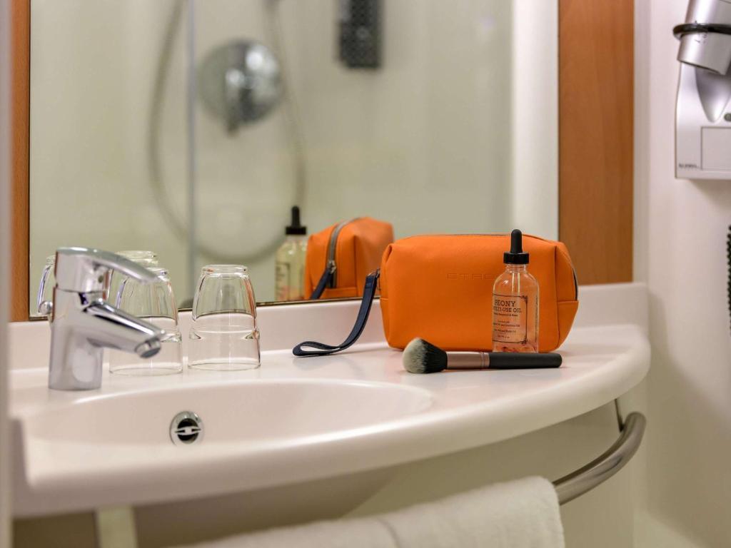 an orange bag sitting on top of a bathroom sink at ibis Stuttgart Airport Messe in Leinfelden-Echterdingen