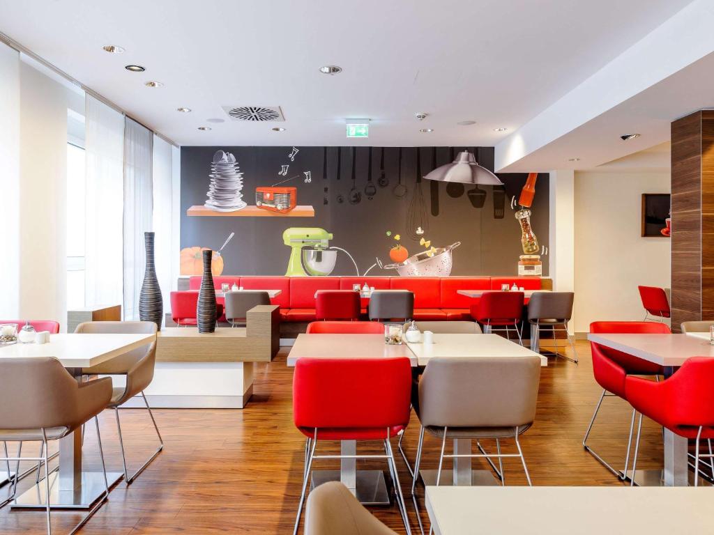 a restaurant with red and white tables and chairs at ibis Stuttgart Airport Messe in Leinfelden-Echterdingen