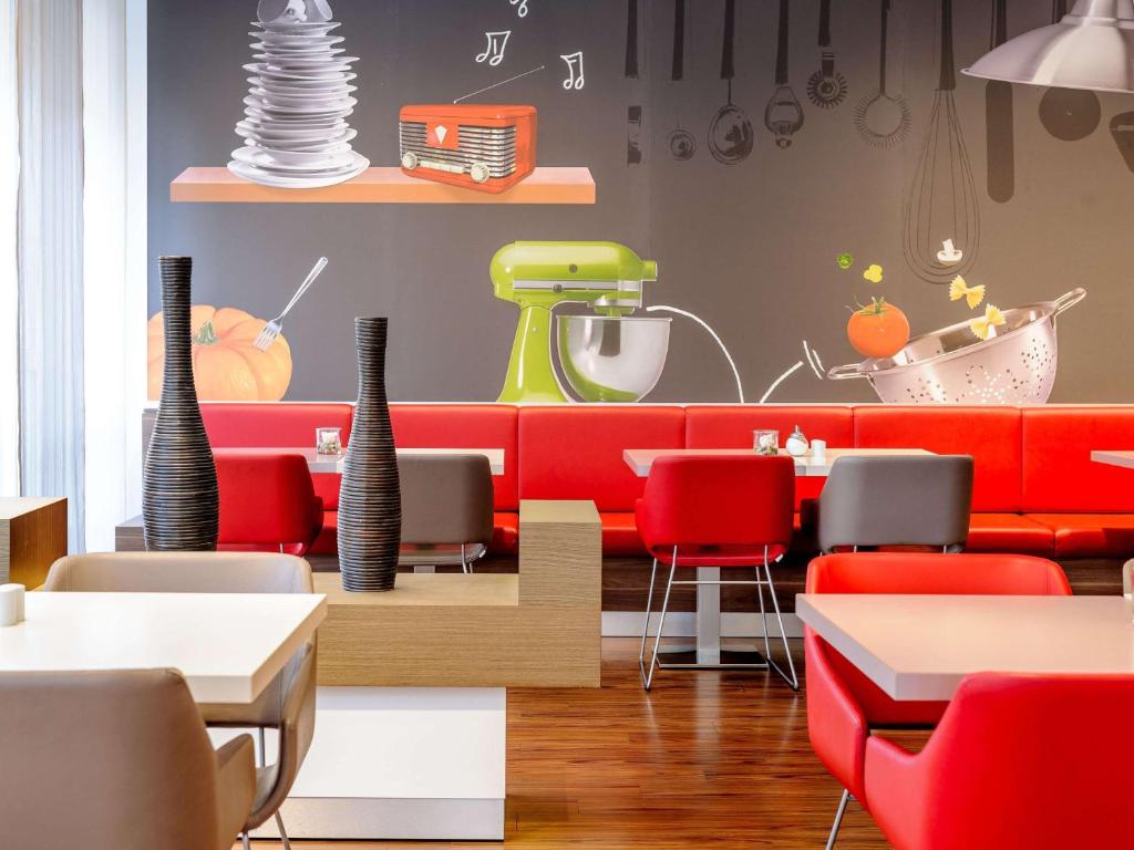 a restaurant with red chairs and a counter with tables at ibis Stuttgart Airport Messe in Leinfelden-Echterdingen