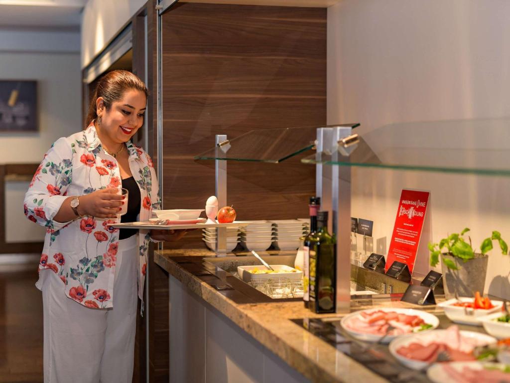 a woman standing in a kitchen preparing food at ibis Stuttgart Airport Messe in Leinfelden-Echterdingen