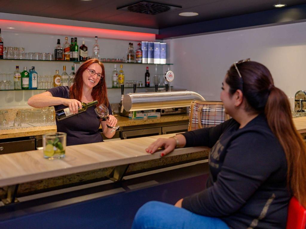 two women sitting at a counter in a bar at ibis Stuttgart Airport Messe in Leinfelden-Echterdingen