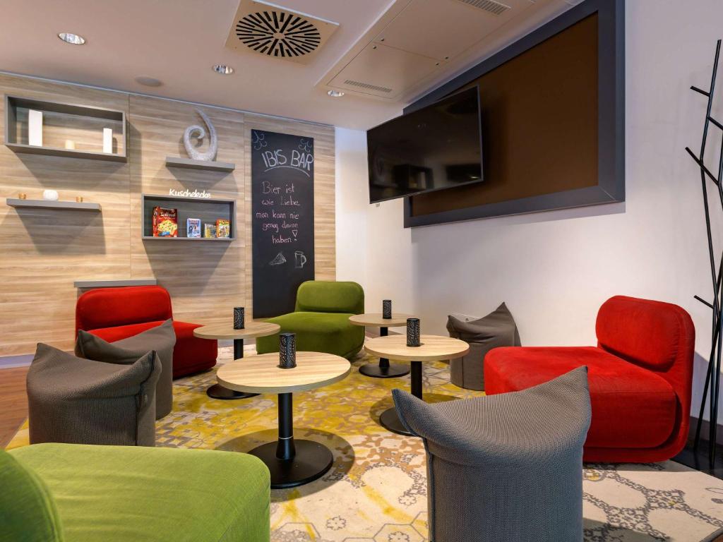 a waiting room with chairs and tables and a tv at ibis Stuttgart Airport Messe in Leinfelden-Echterdingen