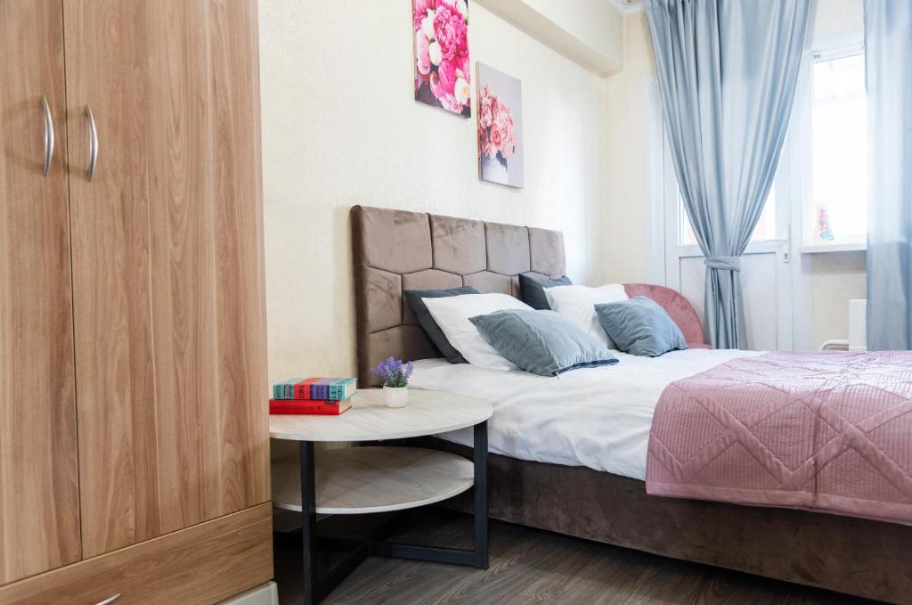 Un dormitorio con una cama con una mesa al lado. en On Arbat the Center of Almaty, en Almaty
