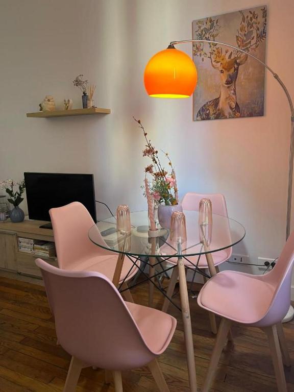 une salle à manger avec une table en verre et des chaises roses dans l'établissement Cosy Haven Paris 14, à Paris