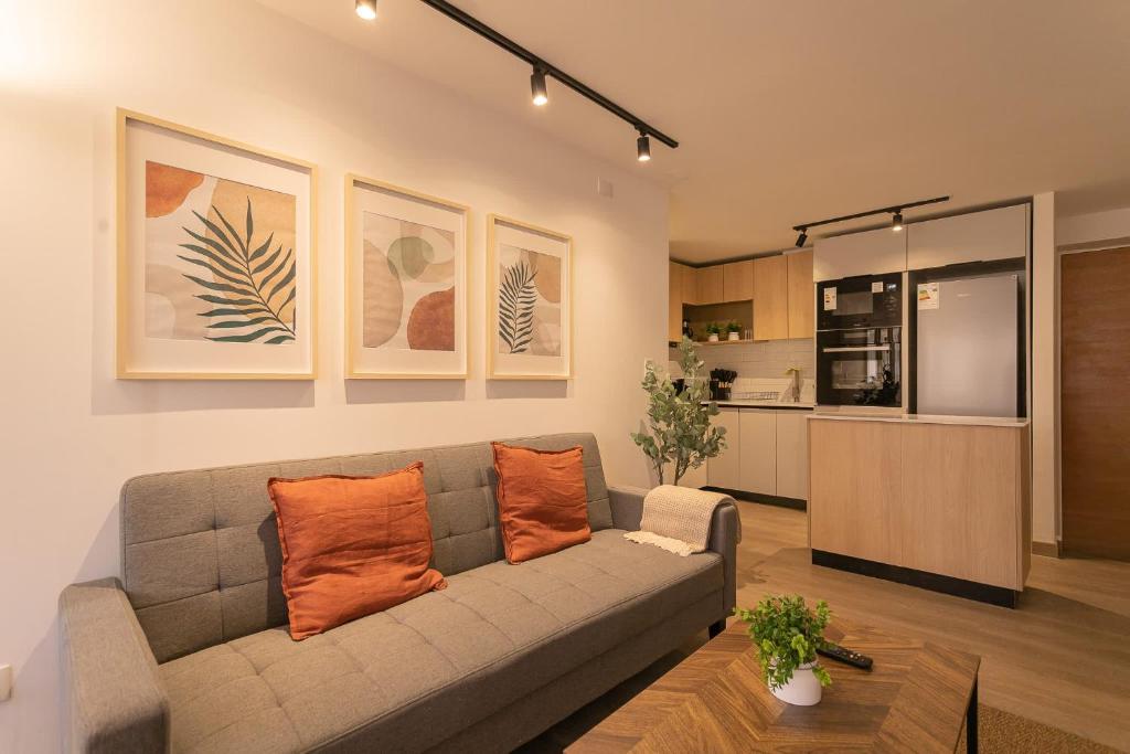 sala de estar con sofá gris y almohadas de color naranja en Elegant 2BR Experience Las Condes in Style, en Santiago