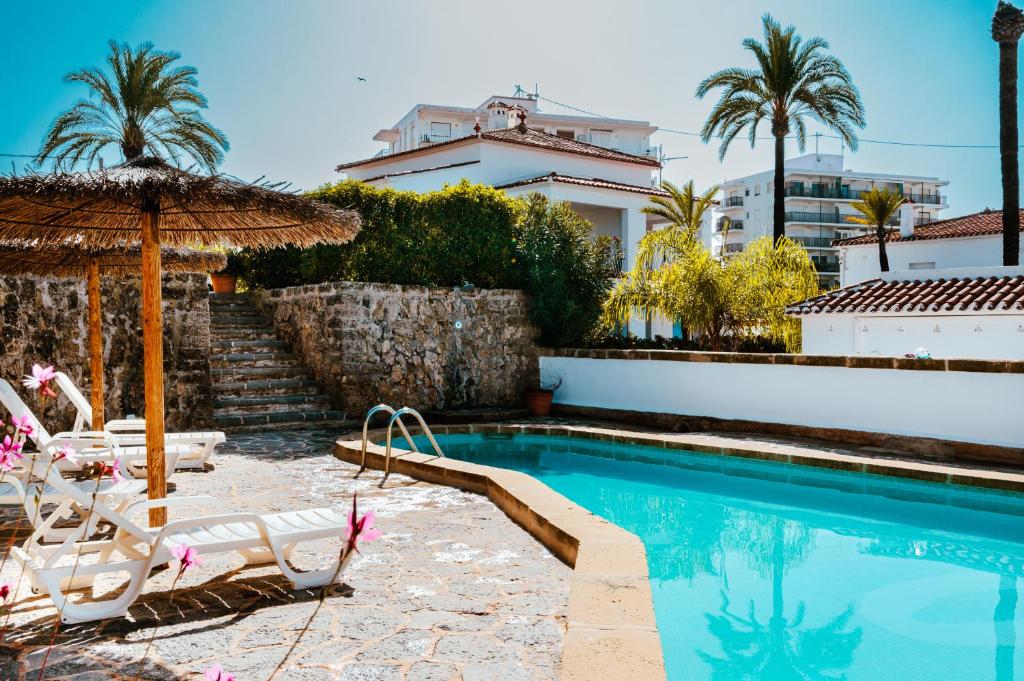 una piscina con sillas y sombrilla en Los Bungalows Del Arenal, en Jávea