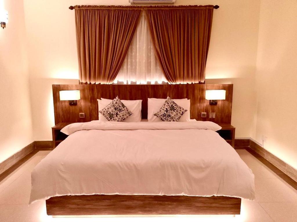 a bedroom with a large white bed with two pillows at Sunrise BnB Creek in Karachi