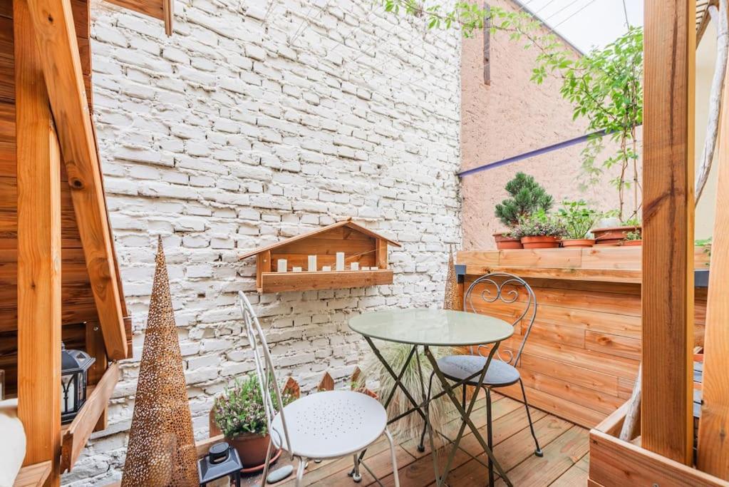un patio avec une table et des chaises et un mur de briques dans l'établissement Magnifique & Cozy appartement au cœur de Strasbourg avec terrasse, à Strasbourg