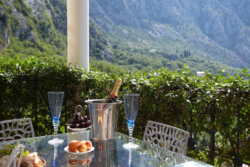 une table en verre avec des verres à vin et un bol de fruits dans l'établissement GREEN HILL 2 Apartmani with POOL, à Gornji Orahovac