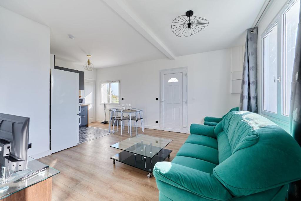 un salon avec un canapé vert et une table dans l'établissement Appartement Évasion Normande - Welkeys, à Cabourg