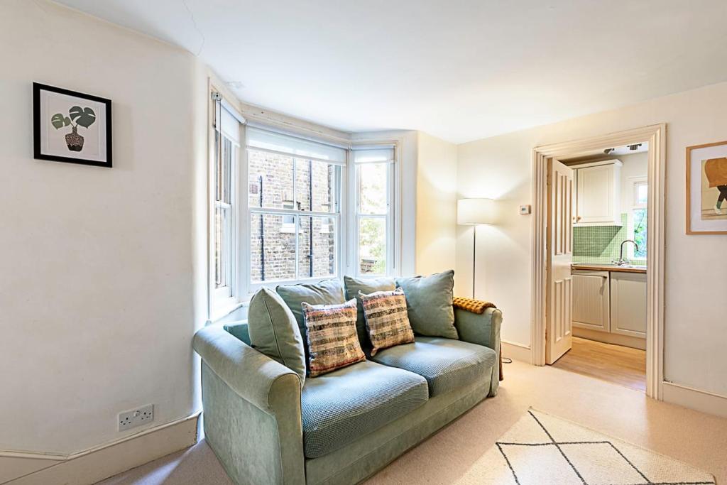 a living room with a blue couch and a window at Cosy Flat in Battersea Park in London