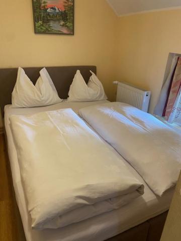 een bed met witte lakens en kussens erop bij Apartman MILI in Požarevac