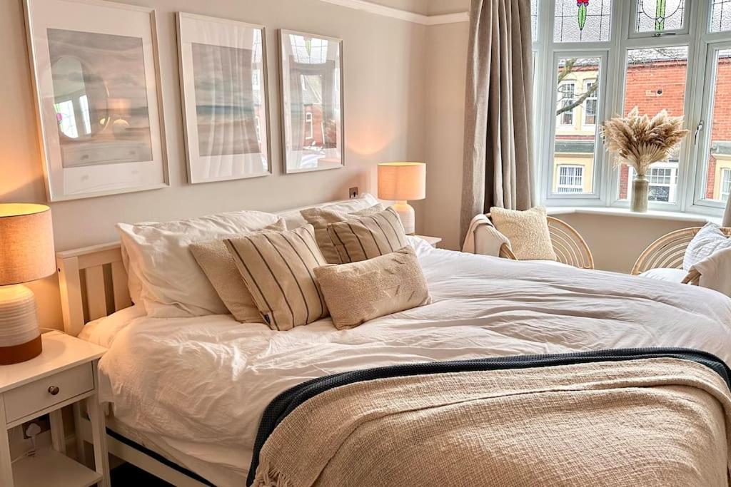a bedroom with a bed with pillows and two windows at Stunning Coastal Retreat Whitley Bay Sleeps 9 in Whitley Bay