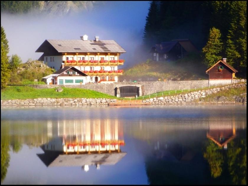 een groot huis naast een grote hoeveelheid water bij Gasthof Gosausee in Gosau