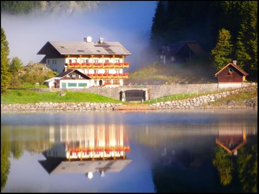 a large house sitting next to a large body of water at Gasthof Gosausee in Gosau