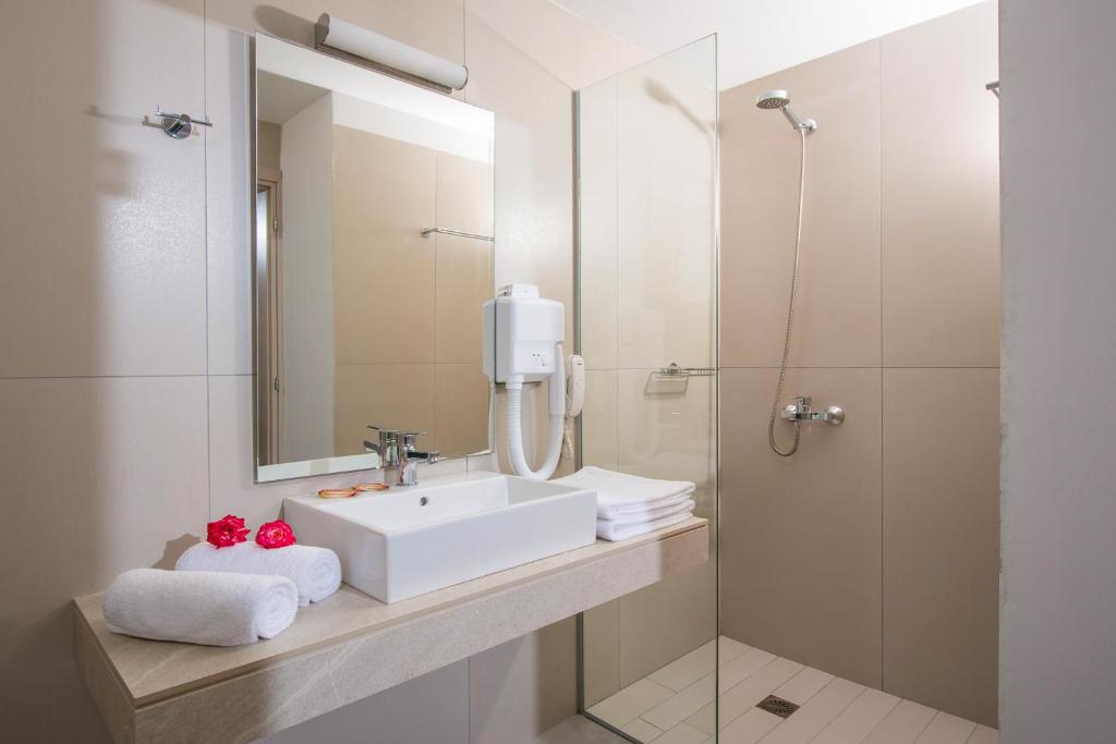 a bathroom with a sink and a mirror and a shower at South Coast Hotel in Makry Gialos
