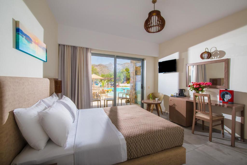 a hotel room with a bed and a desk with a table at South Coast Hotel in Makry Gialos