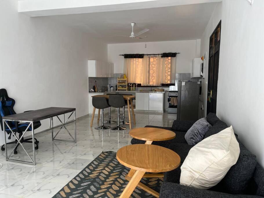 a living room with a couch and a table and a kitchen at Nani Coastal Retreat Modern Bungalow with Terrace in Kilifi