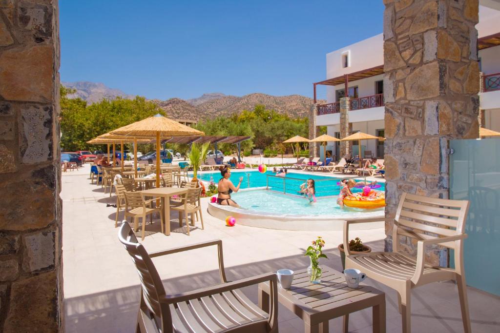 a resort with a pool with tables and chairs at South Coast Hotel in Makry Gialos