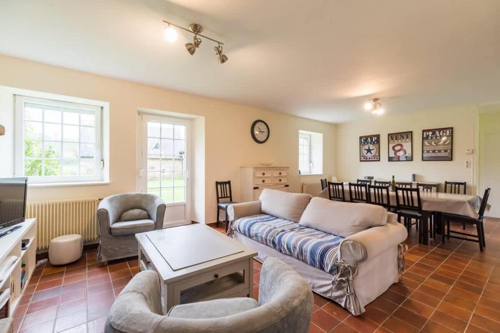 ein Wohnzimmer mit Sofa, Stühlen und einem Tisch in der Unterkunft Charmante maison la Tissanderie a Saint-Carreuc in Saint-Carreuc