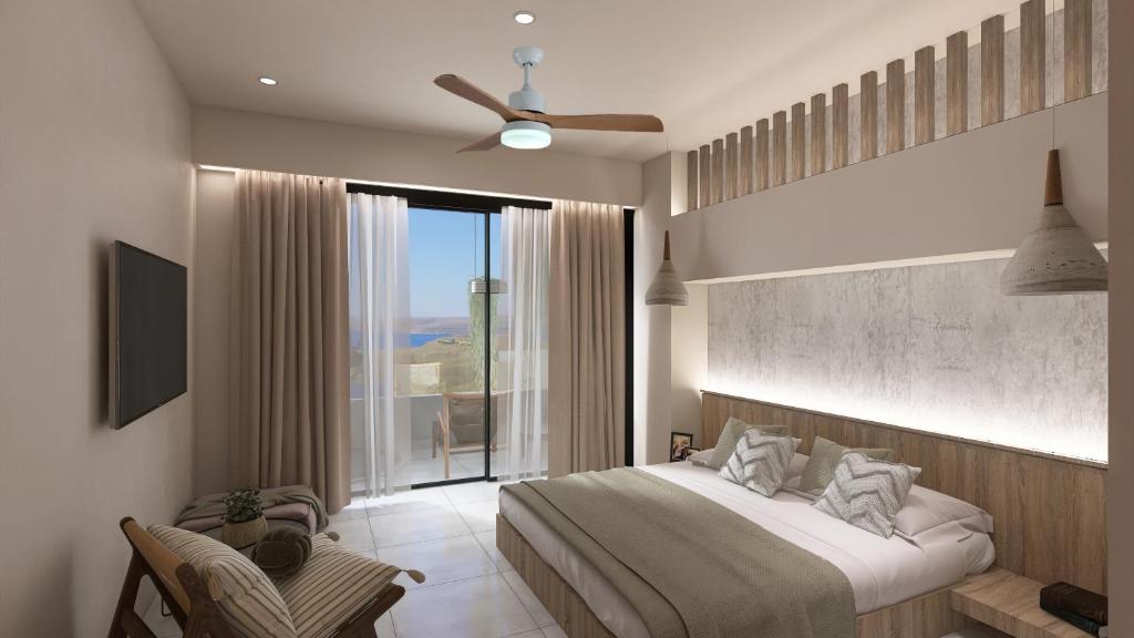 a bedroom with a large bed and a large window at South Coast Hotel in Makry Gialos
