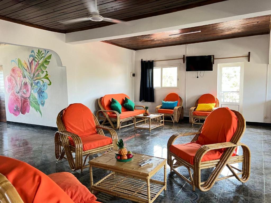 a waiting room with orange chairs and a table at VaoVao Hotel in Nosy Be