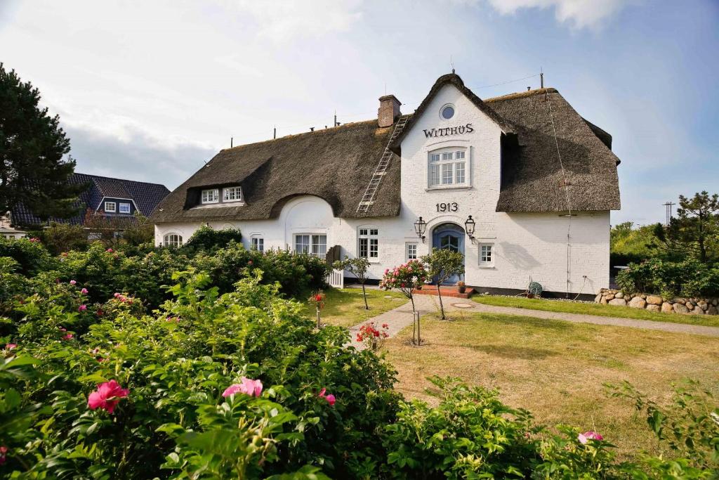 een groot wit huis met een rieten dak bij Witthüs 15 in Wenningstedt