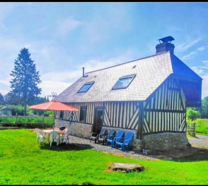 une maison avec deux chaises et une table devant elle dans l'établissement Bienvenue à la maison, à Le Theil-en-Auge