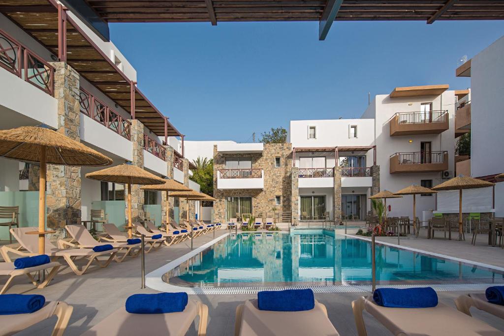 a pool with chairs and umbrellas in a hotel at South Coast Hotel in Makry Gialos