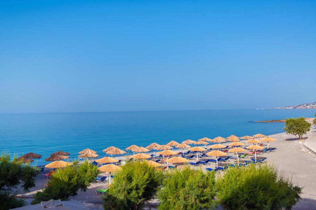 a beach with umbrellas and the ocean at South Coast Hotel in Makry Gialos