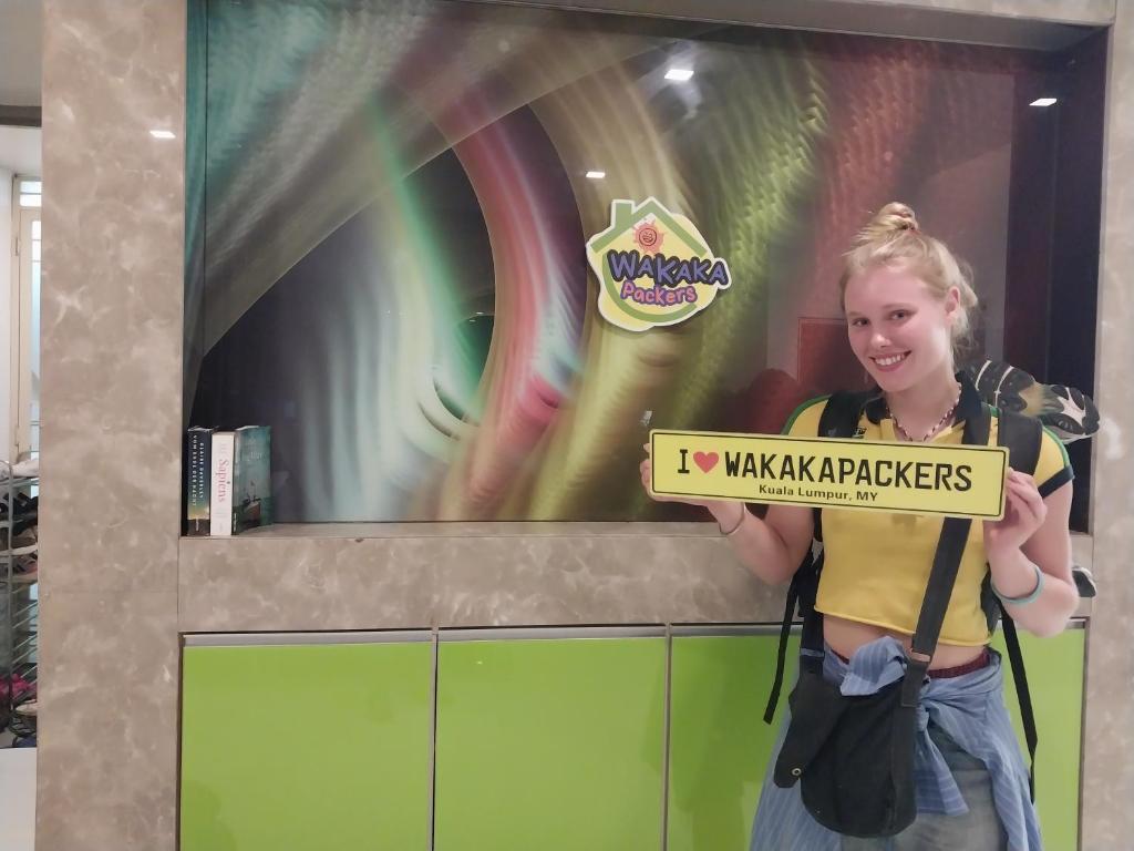 a woman holding a sign that says kawakakellers at WakakaPackers in Kuala Lumpur