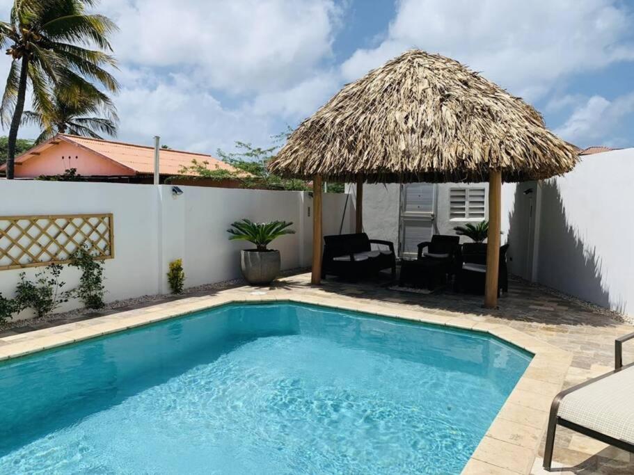 a small swimming pool with a thatched umbrella and chairs at Turibana Villa- 3 Bedroom, 2 Bathroom in Palm-Eagle Beach