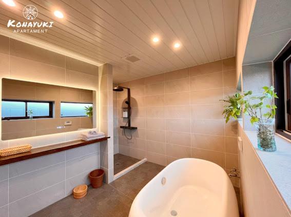 a bathroom with a tub and a toilet and a sink at KONAYUKI Apartment in Myoko